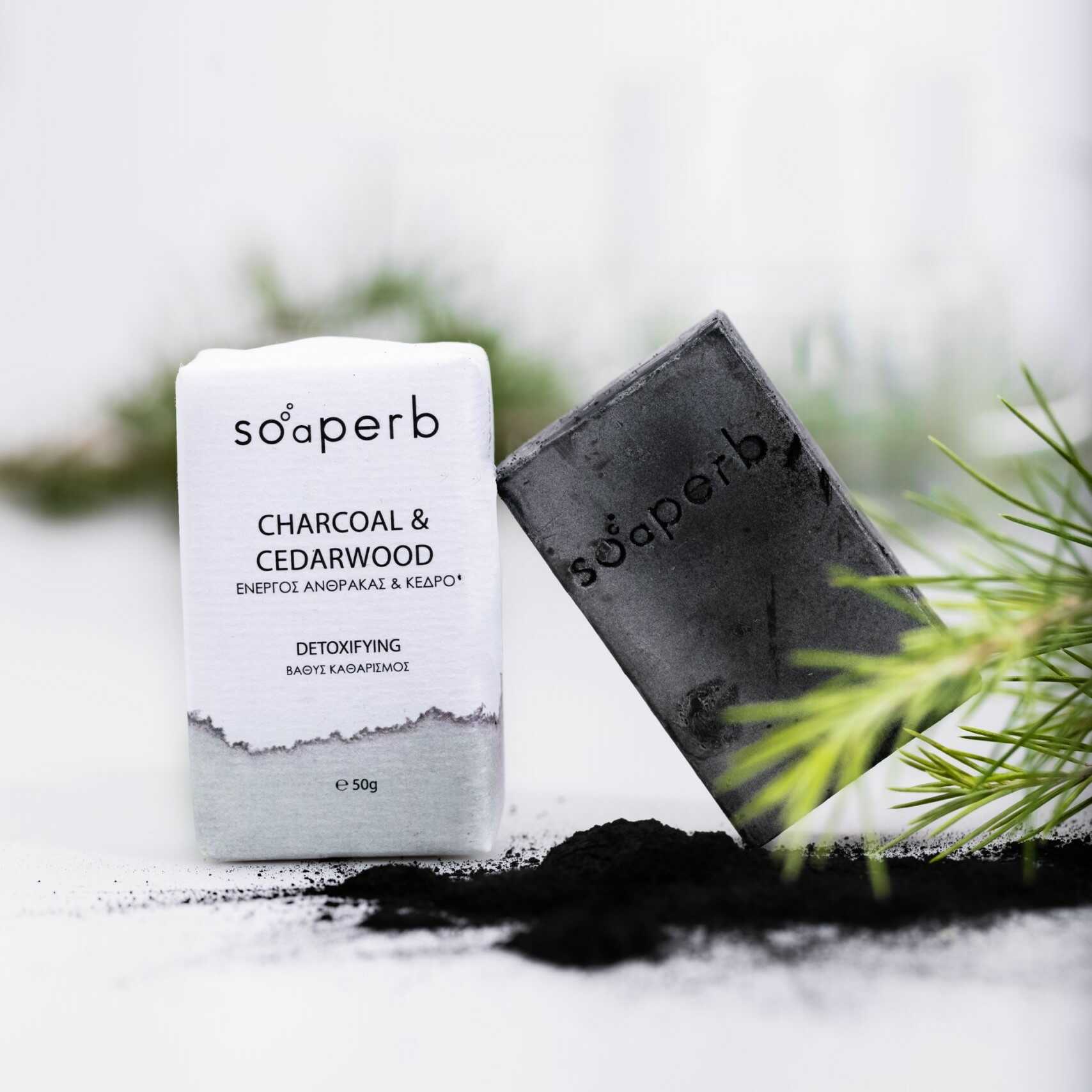 Natural detoxifying soap bar with charcoal and cedarwood by Soaperb, ideal for oily and problem skin – displayed with packaging and black charcoal powder.